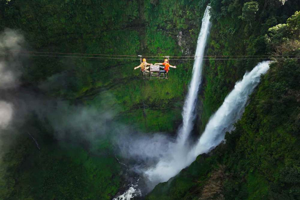 Deux touristes font de la tyrolienne au-dessus de la cascade de Tad Fane, au Laos